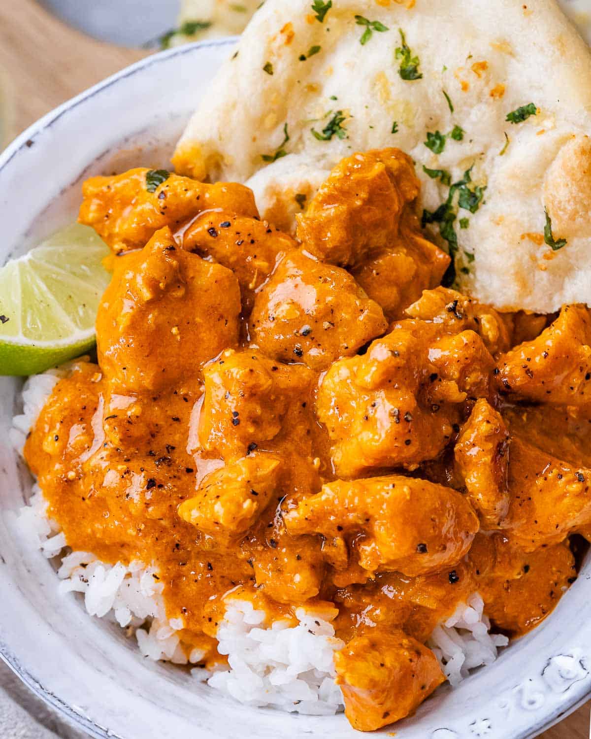 chicken curry served over rice in a bowl with naan.