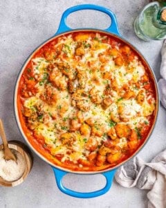A blue skillet of creamy chicken gnocchi on a grey worktop.