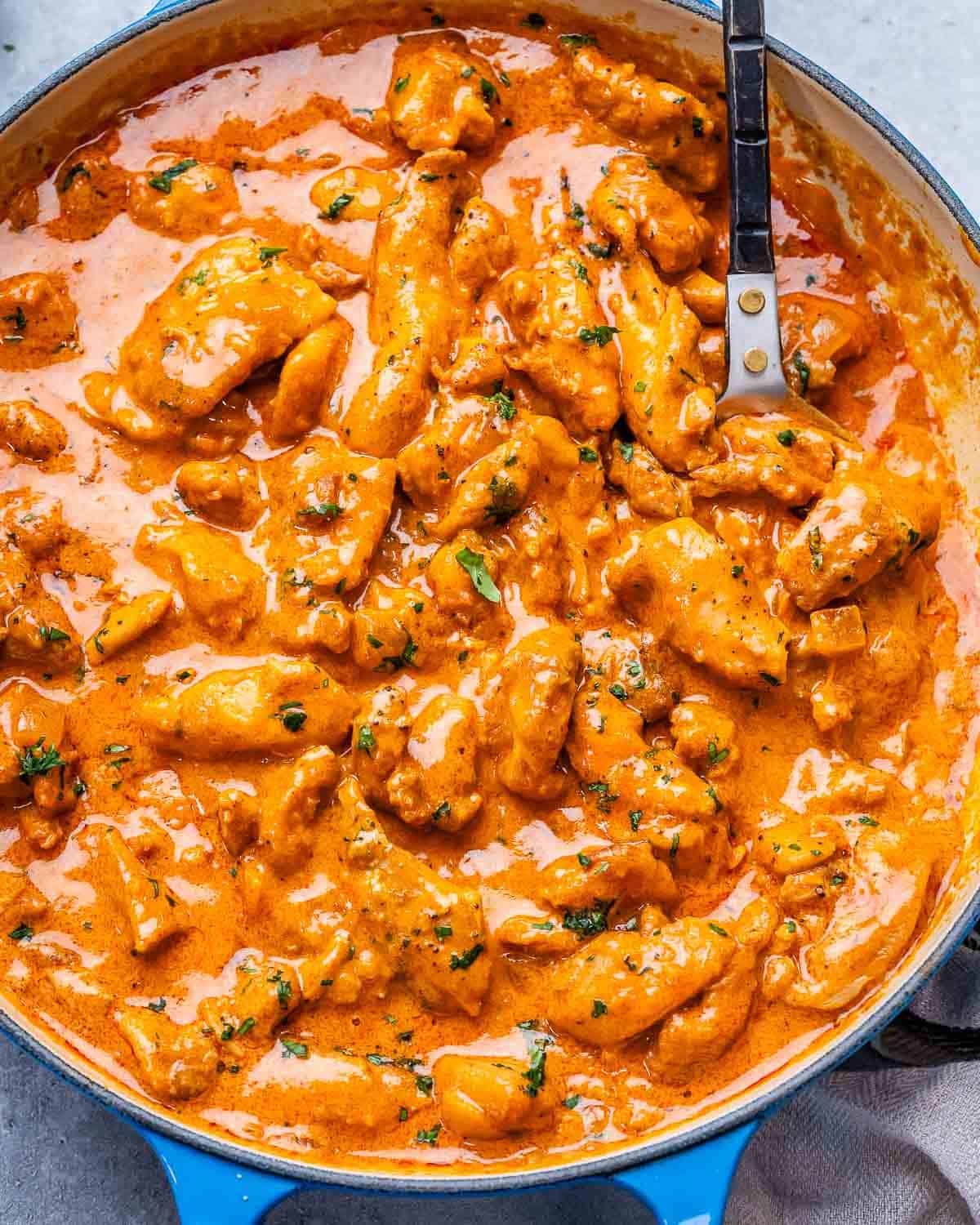 A close up of chicken paprikash in a blue skillet.