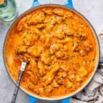 a skillet with chicken bites cooked in a creamy orange paprika sauce.