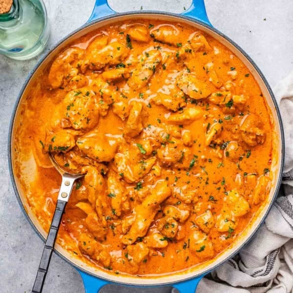a skillet with chicken bites cooked in a creamy orange paprika sauce.