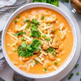 a bowl with crack chicken chili topped with shredded cheese and cilantro.