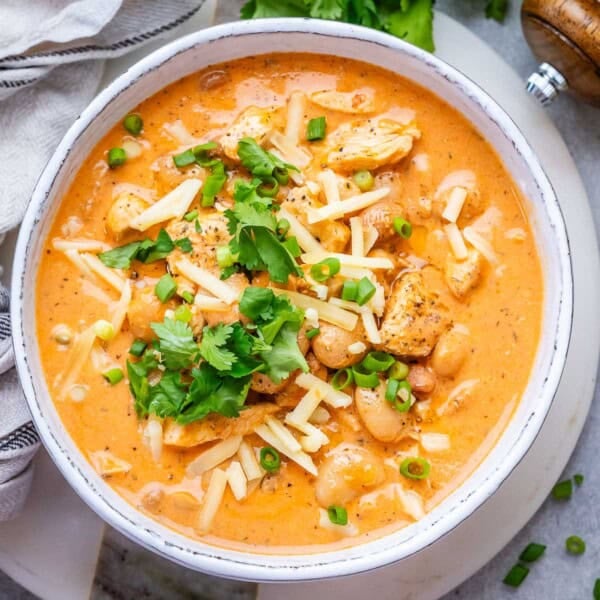 a bowl with crack chicken chili topped with shredded cheese and cilantro.