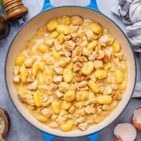 gnocchi and chicken in a creamy sauce in a blue pan.