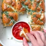 garlic hawaiian bread in a dish with pizza red sauce in the middle to serve it with.