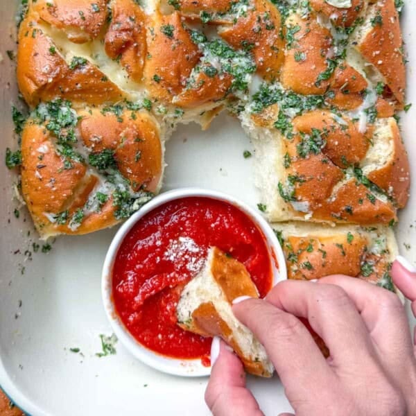 garlic hawaiian bread in a dish with pizza red sauce in the middle to serve it with.