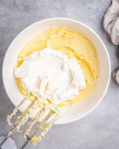 adding ricotta cheese over the blended butter and sugar.