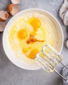 adding eggs and vanilla into the batter in a bowl before whisking.