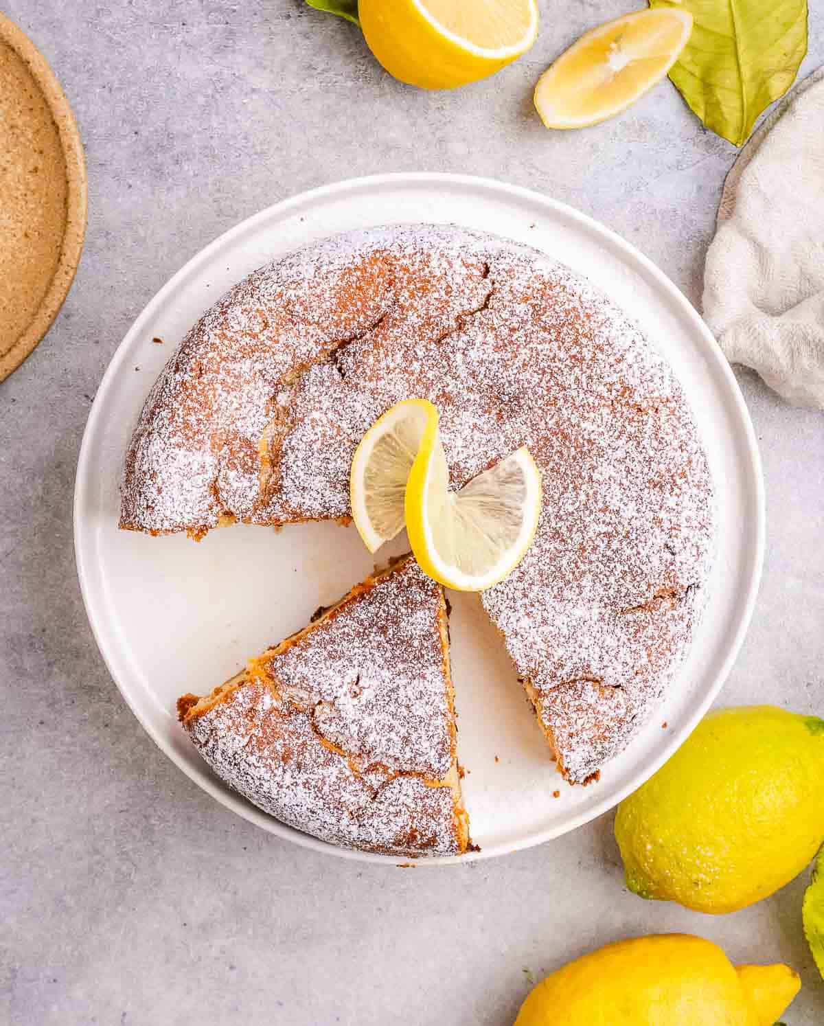 lemon cake on a plate with a piece cut off.