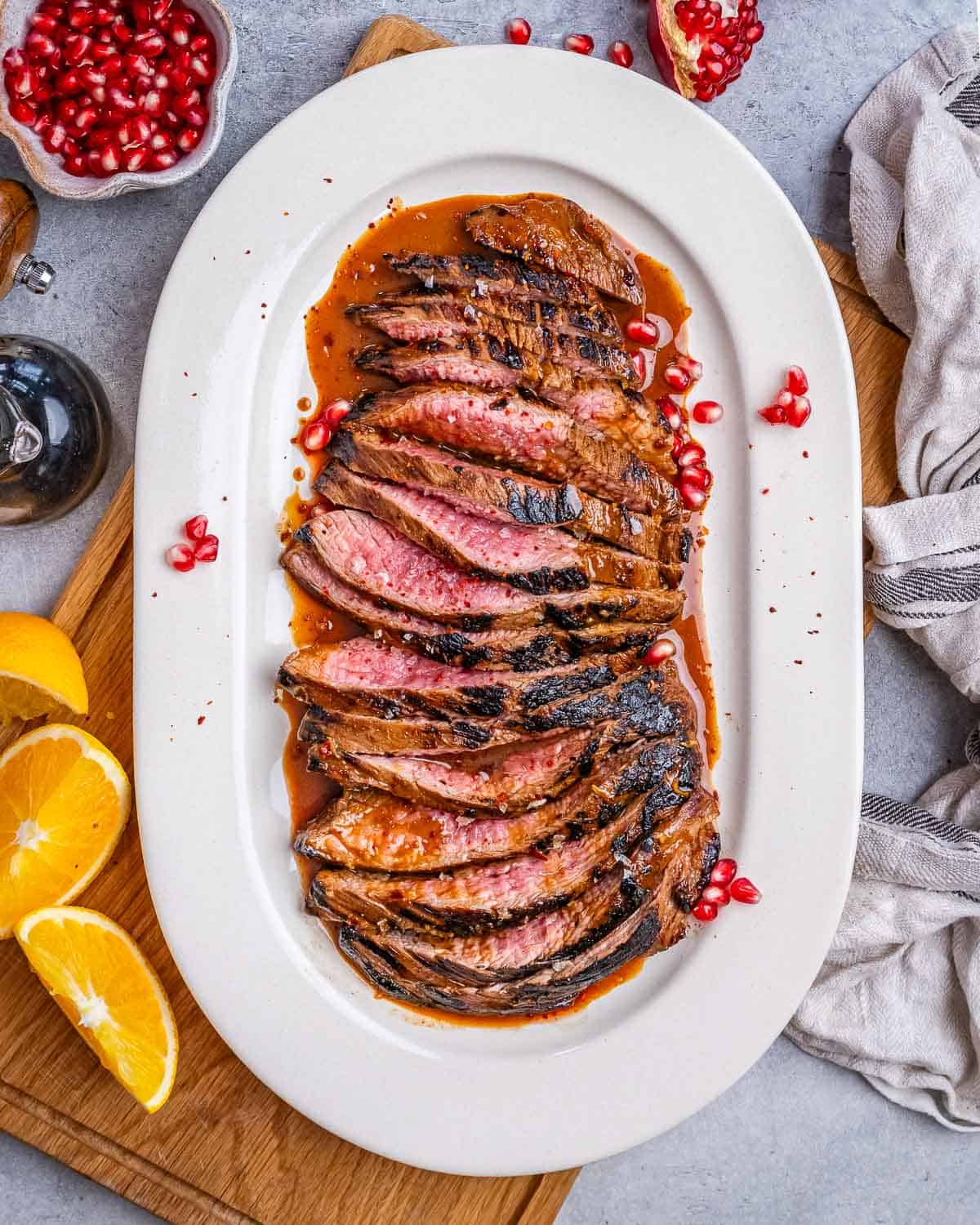 an oval white plate with sliced steak in a brown marinade.