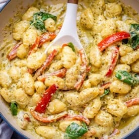 gnocchi in creamy pesto sauce in a skillet.