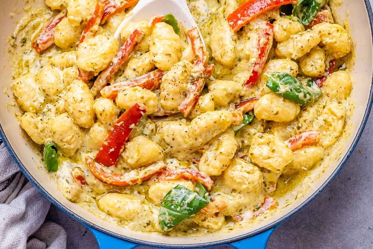 pesto gnocchi in a skillet with a spoon in the skillet.  