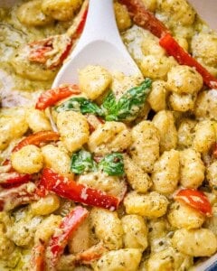 Pesto gnocchi in a pan with a spoon.