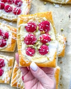 hand holding a cheese and raspberry danish.