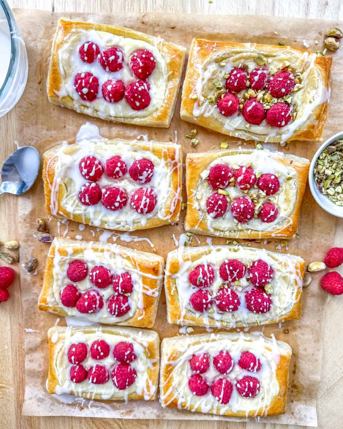 8 cheese danishes topped with fresh raspberries, a drizzle of glaze, and chopped pistachios.