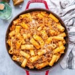 a red skillet with pasta and red beef sauce.