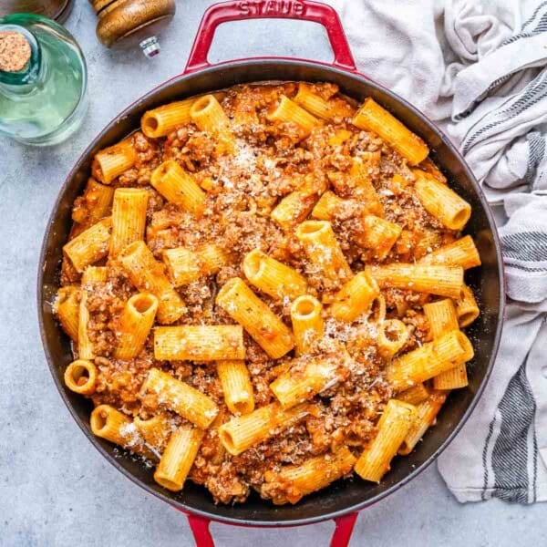 a red skillet with pasta and red beef sauce.