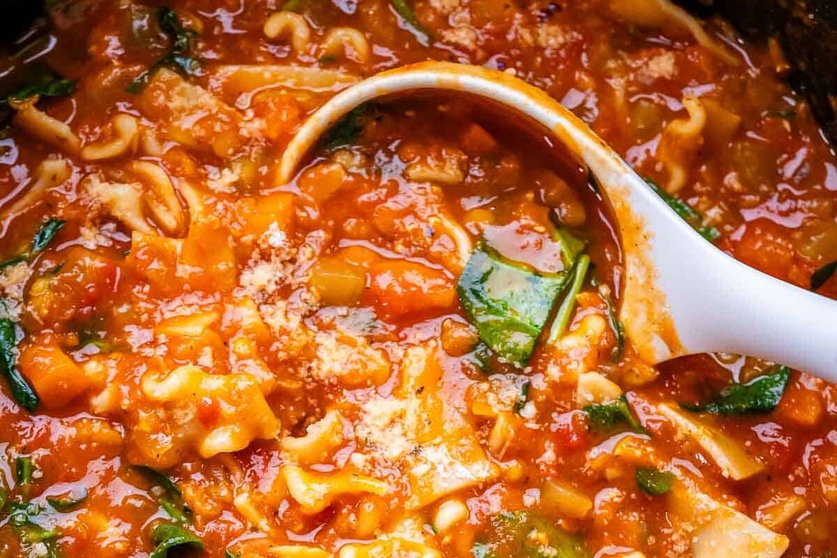 A green pot with vegetarian lasagna soup and white ladle.