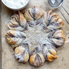 cinnamon roll snowflake on a sheet pan topped with powdered sugar.