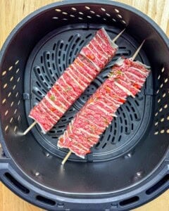 two tortilla kebab skewers in the air fryer basket.