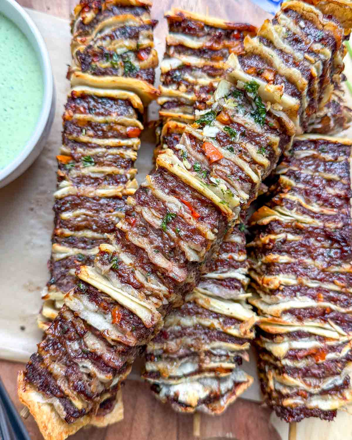 air fried tortilla kebabs stacked on a wooden board.