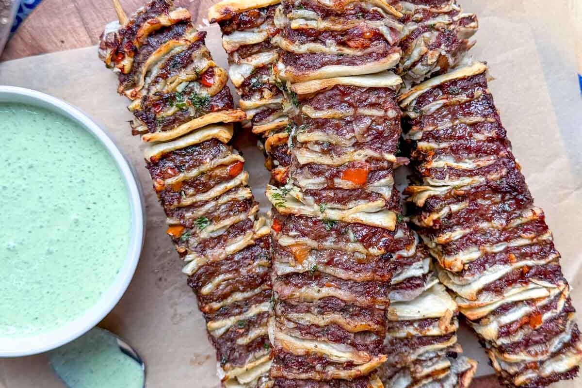 tortilla kebabs on a cutting board with yogurt dip on the side.