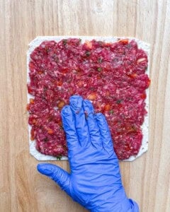 ground beef being spread over the tortilla.