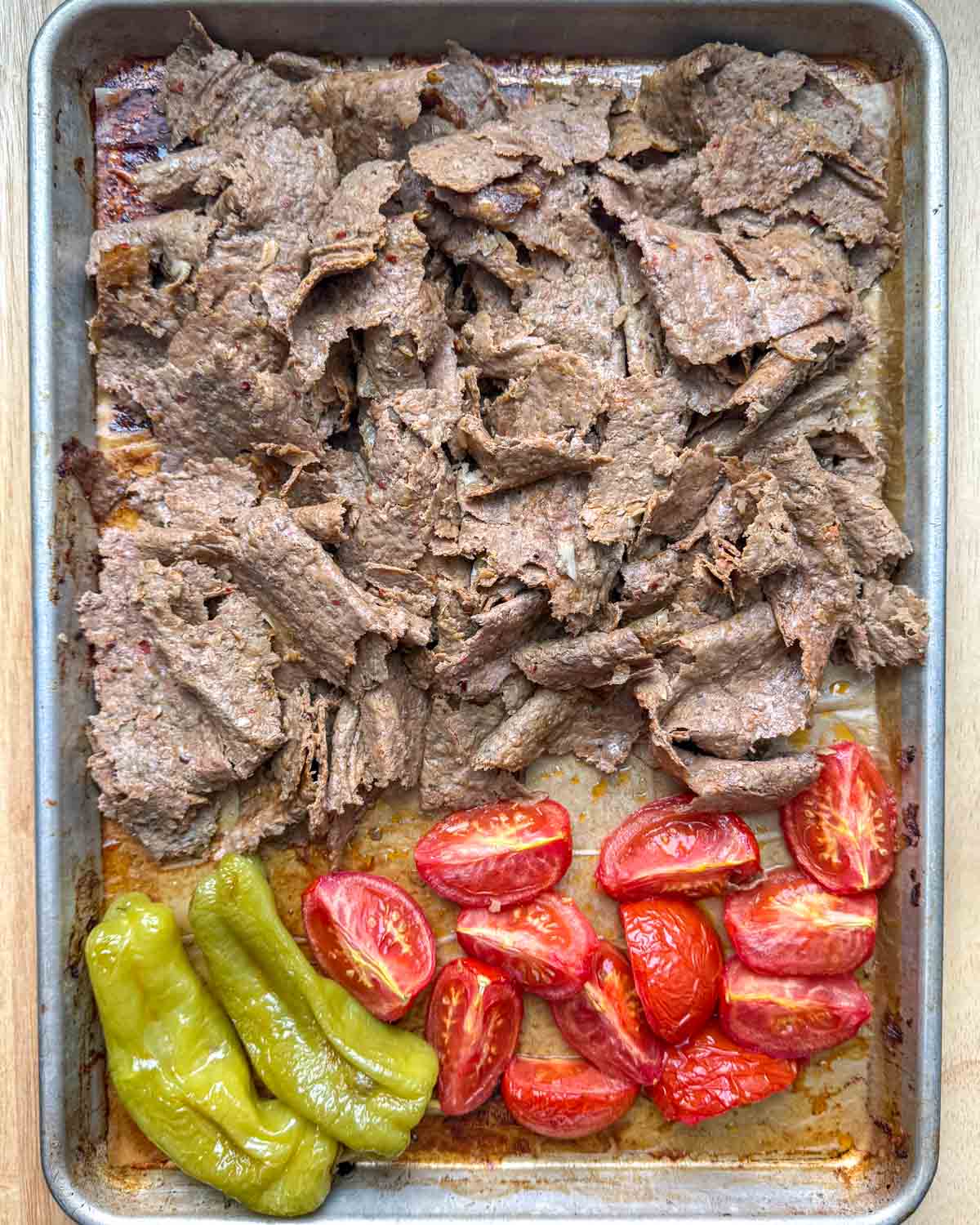 shredded doner kebab on a pan with tomatoes and pepper baked on the side.