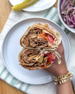 holding the sandwich that's cut in half.