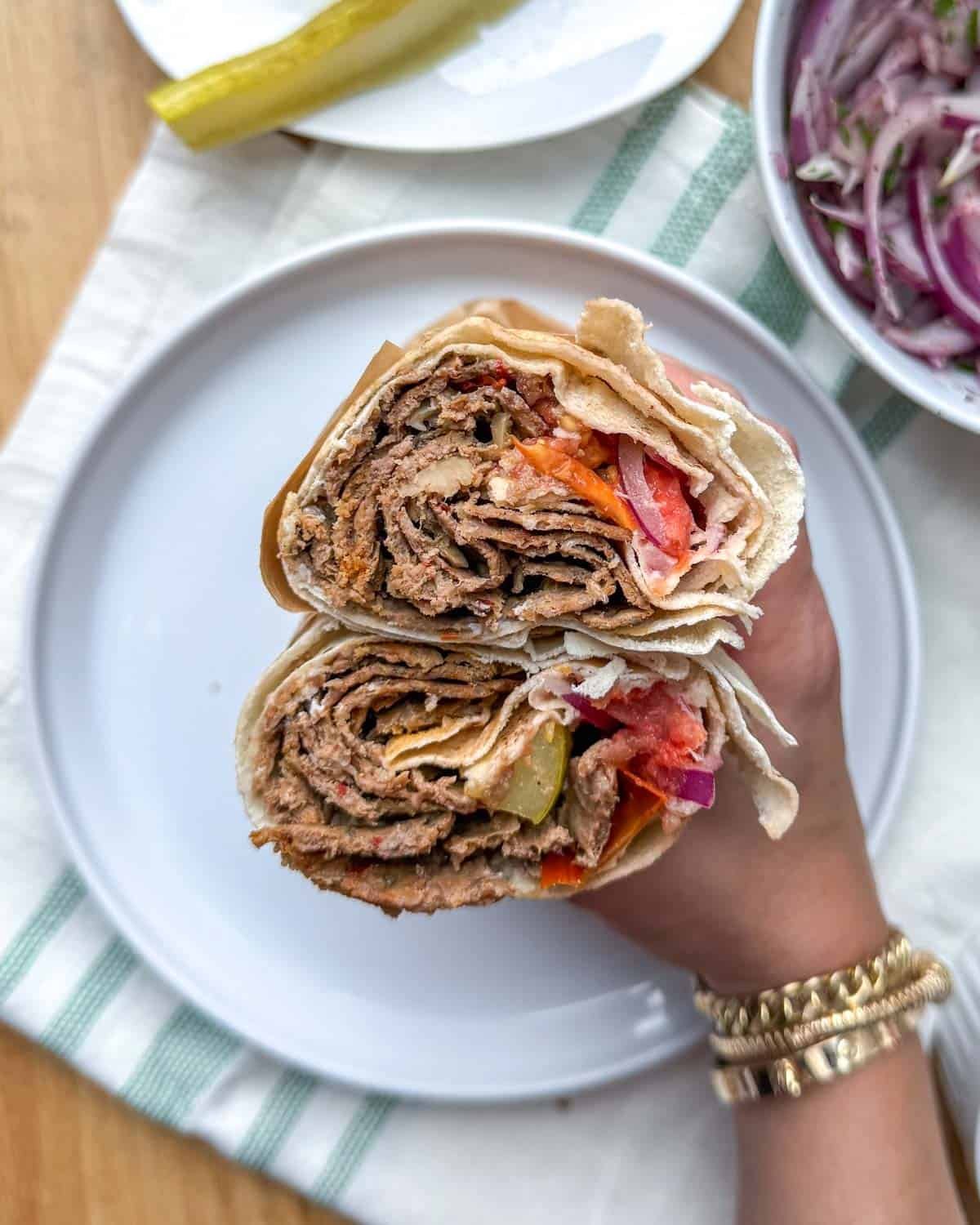 holding the sandwich that's cut in half.