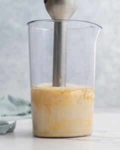 Immersion blender continuing to blend, with the mayonnaise now mostly thick and smooth inside the jar.