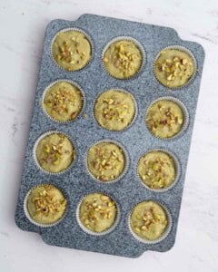 pistachio muffin batter in muffin pan.
