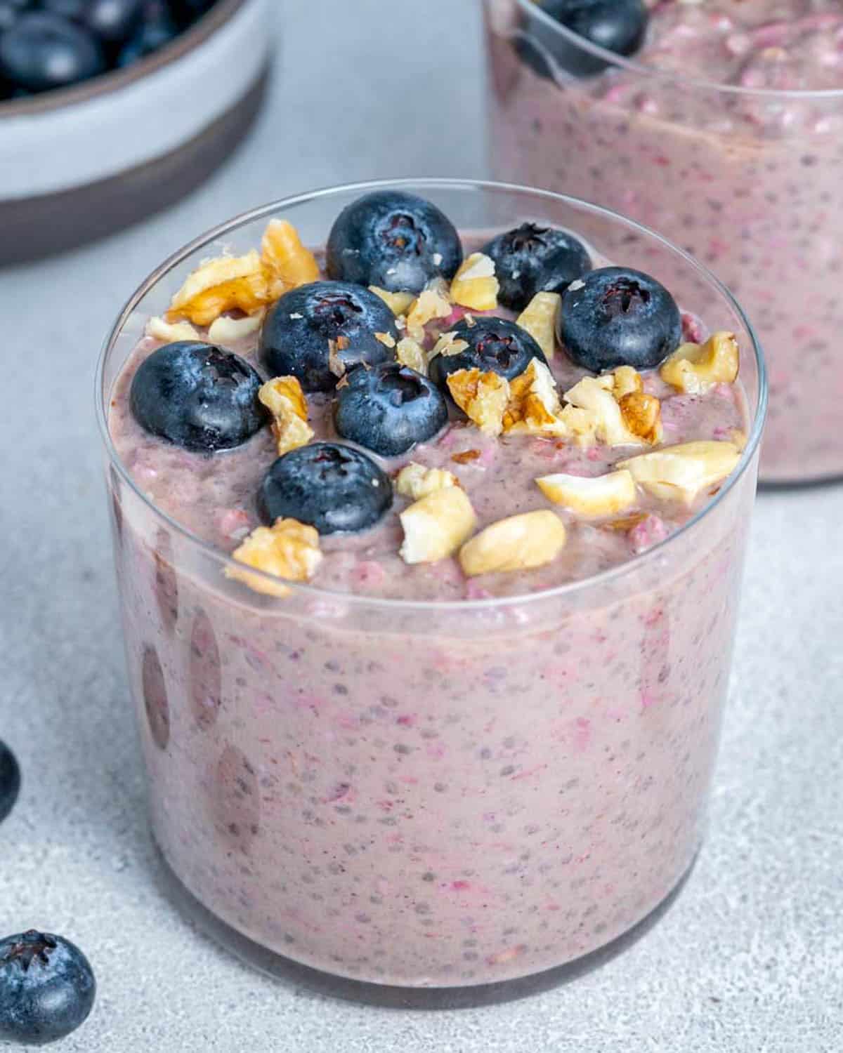a cup with blueberry overnight oats, topped with fresh berries and nuts.