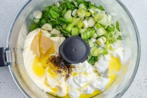 ingredients for the green goddess dressing placed in a food processor to be blended.