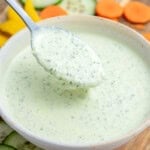 a spoon full of green goddess dressing from a bowl.