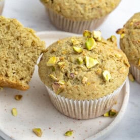 a green pistachio muffin on a white plate.