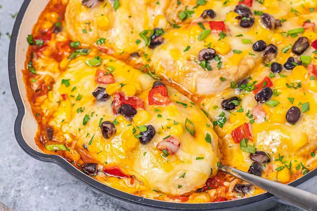 chicken breasts in a red santa fe sauce topped with melted cheese and diced green onions. 