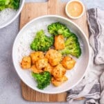 a round bowl with rice, topped with broccoli and bang bang salmon bites.
