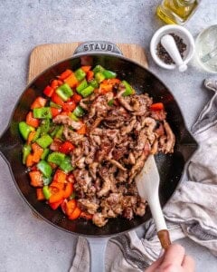 combining pepper and cooked seasoned beef in a skillet.