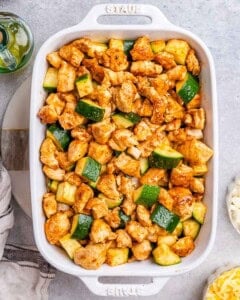 seared chicken added over the zucchini in a baking dish.