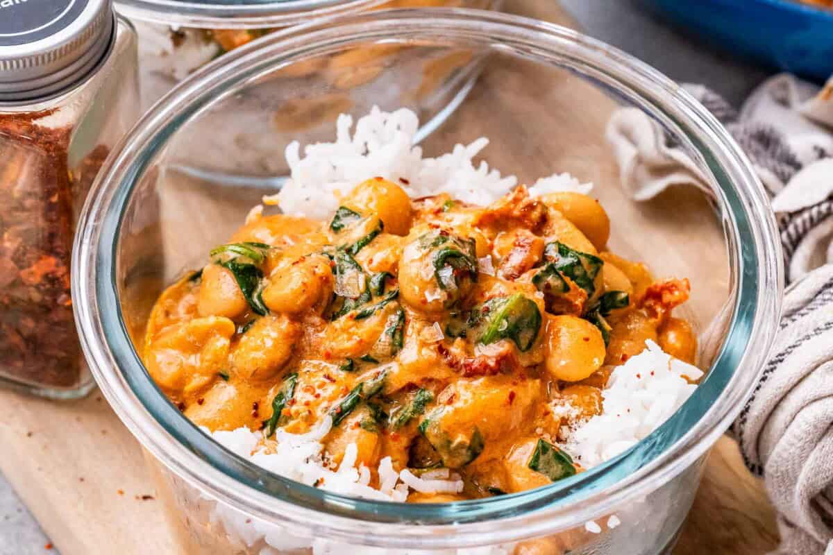 a clear bowl with marry me butter beans served over white rice.