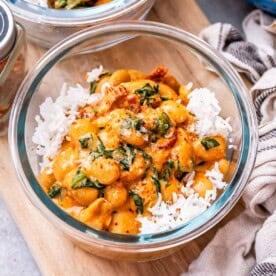 a meal prep glass bowl with marry me butter beans served over white rice.
