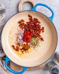 sun-dried tomatoes, garlic, herbs, and seasonings, placed in a skillet to be cooked.