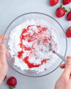strawberry puree being added over powdered sugar.