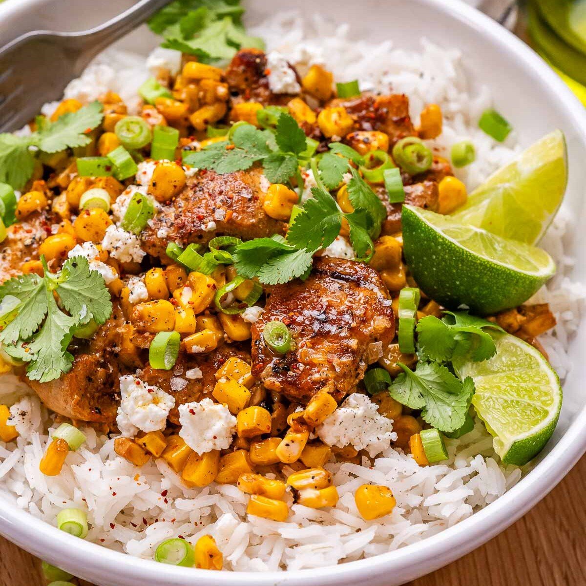a rice bowl topped with seared chicken mixed with street corn salad.