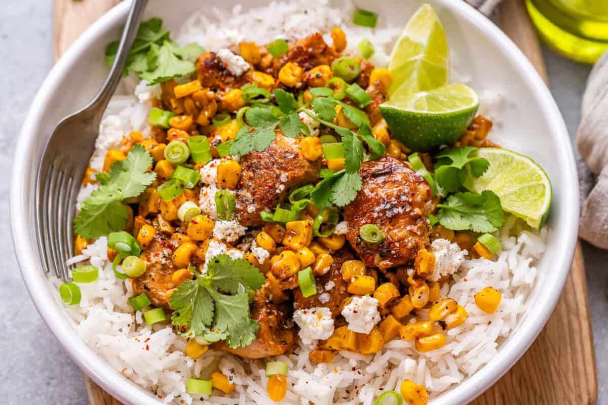 street corn chicken and rice in a bowl garnished with cilantro and sliced green onions.