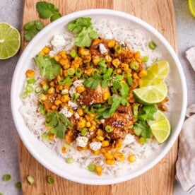 a round bowl with chicken and corn, served over white rice,