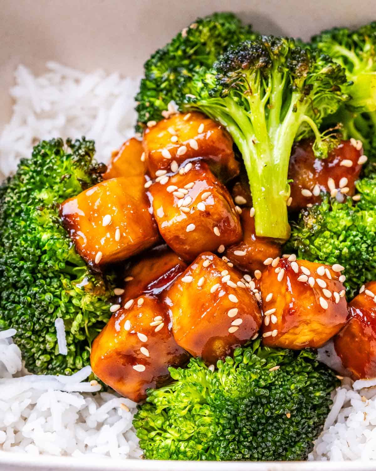 a bowl of rice topped with bake broccoli and teriyaki tofu bites.