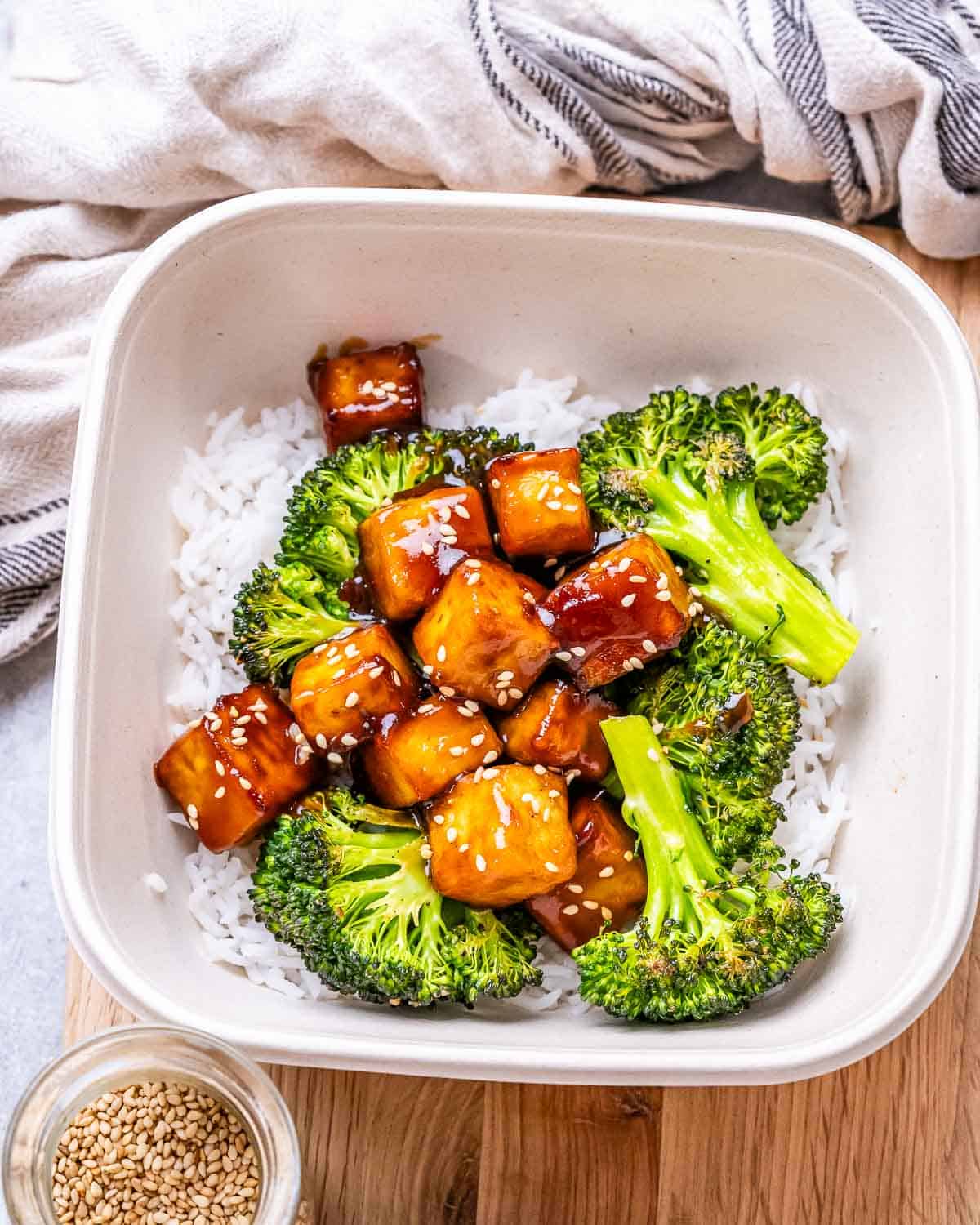 a white bowl with teriyaki tofu served over white rice and roasted broccoli.