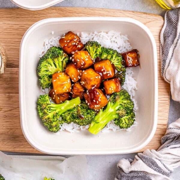 a meal prep bowl with white rice topped with teriyaki tofu bites and roasted broccoli.
